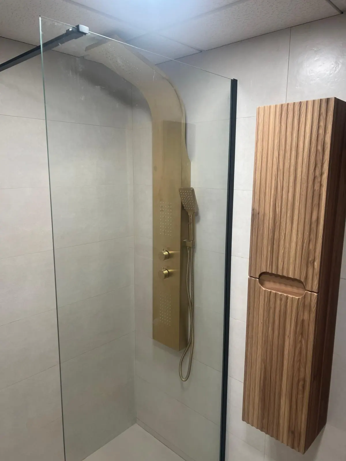 Baño con columna de ducha dorada